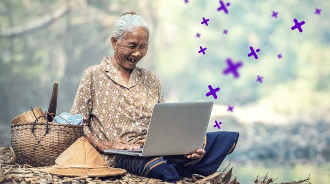 Donna anziana seduta nella foresta al suo computer portatile con facile accesso per il pubblico virtuale globale