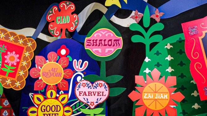 Addio in diverse lingue in fiori di carta colorati come simbolo del multilinguismo